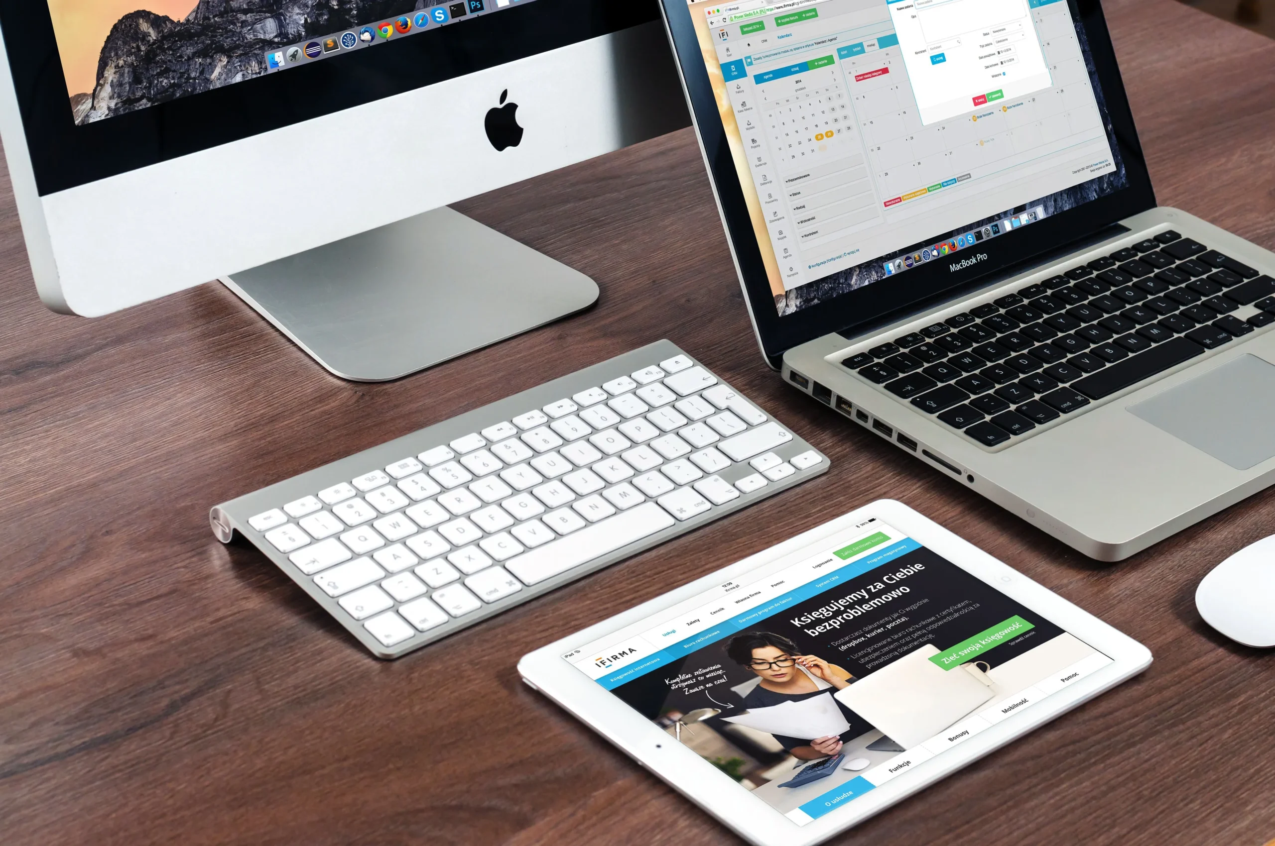 Arbeitsplatz mit Desktop-PC, Laptop und Tablet, die eine Website und Business-Software auf verschiedenen Geräten anzeigen.